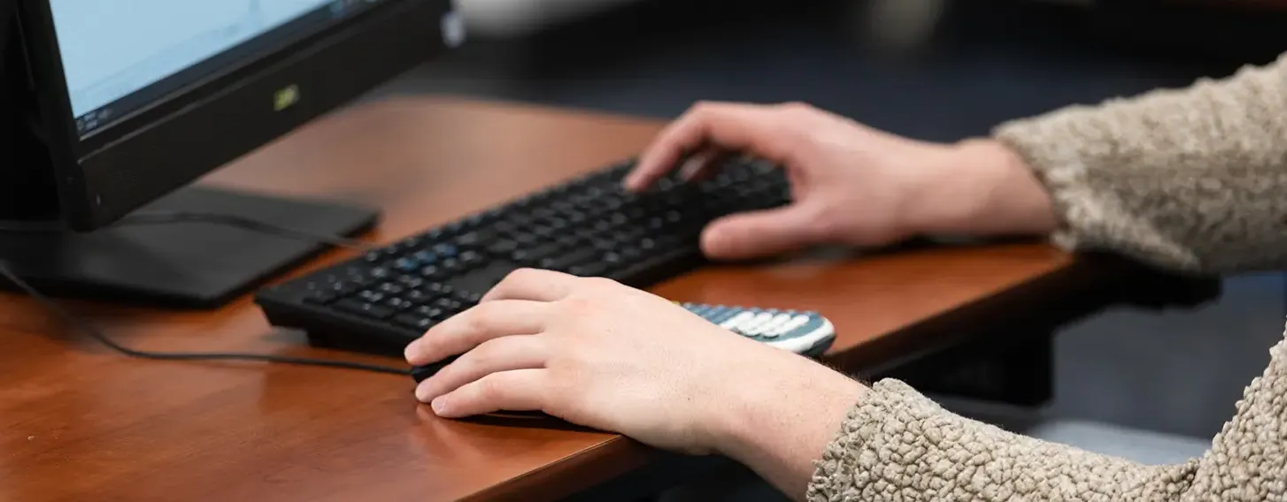 A student typing at a computer on a keyboard